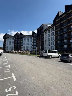 a parking lot with cars parked in front of buildings at Andromeda Apartment Residence Hill Kopaonik in Kopaonik