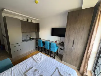 a room with a bed and a kitchen with blue chairs at Andromeda Apartment Residence Hill Kopaonik in Kopaonik