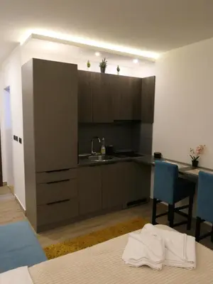 a kitchen with a sink and a table with blue chairs at Andromeda Apartment Residence Hill Kopaonik in Kopaonik