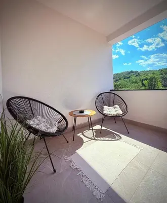 two chairs and a table in a room with a window at DUNjA Apartman in Vrnjačka Banja
