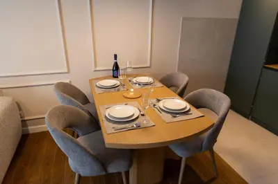 a dining room table with chairs and a bottle of wine at Planet Imperial Apartman & SPA in Niš