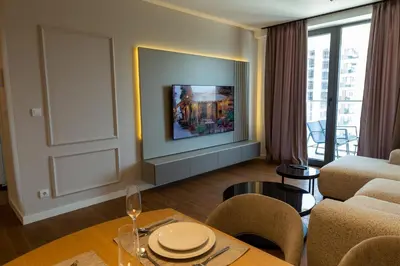 a living room with a couch and a table and a tv at Planet Imperial Apartman & SPA in Niš