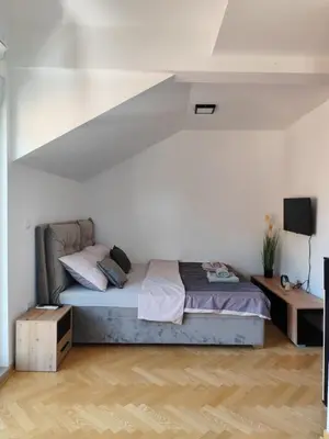 a bedroom with a bed and a white wall at Raj M&M in Vrnjačka Banja