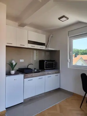a kitchen with white cabinets and a window at Raj M&M in Vrnjačka Banja