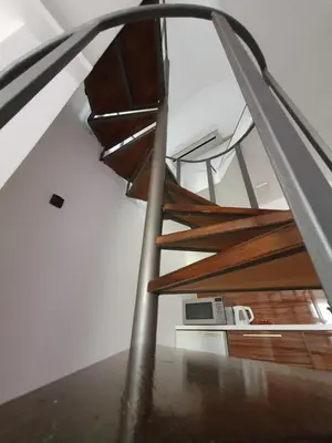 a spiral wooden staircase in a house with a microwave at Niš City Center Guest House in Niš