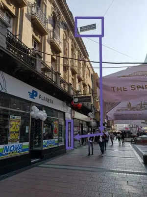 a street with buildings and people walking on the sidewalk at Niš City Center Guest House in Niš
