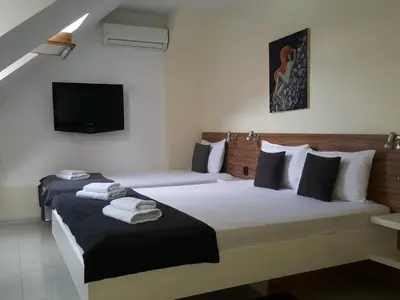 a hotel room with two beds and a tv at Niš City Center Guest House in Niš