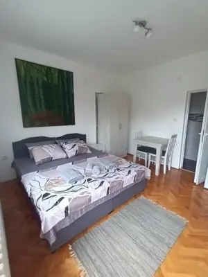a bedroom with a large bed and a table at Apartmani Bata I Seka in Vrnjačka Banja