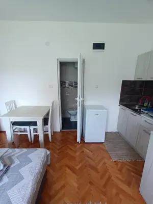a kitchen with a table and a white refrigerator at Apartmani Bata I Seka in Vrnjačka Banja