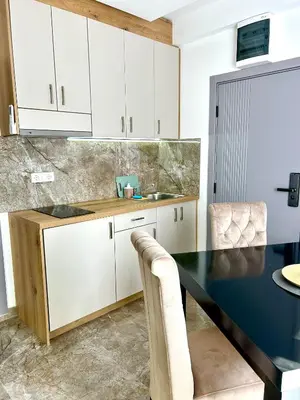 a kitchen with white cabinets and a black table at L apartmani in Soko Banja
