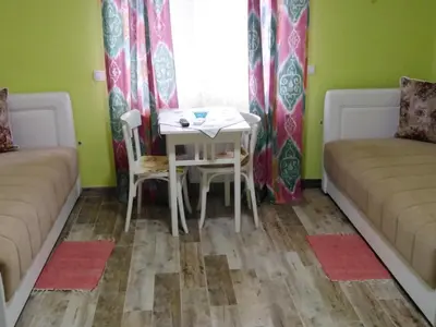 a room with a table and two beds and a table and chairs at Apartmani Lucky in Vrnjačka Banja