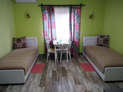 a room with two beds and a table and a window at Apartmani Lucky in Vrnjačka Banja