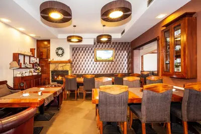 a restaurant with wooden tables and chairs and a fireplace at HostGost at Kraljevi Čardaci in Kopaonik