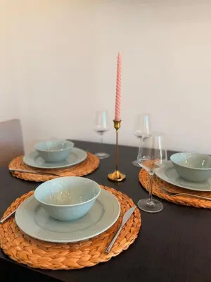a table with four bowls and plates and wine glasses at Natalie Apartment in Niš