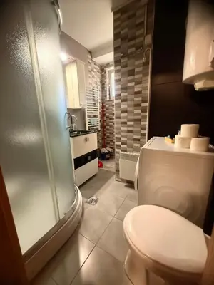a bathroom with a toilet and a glass shower at Natalie Apartment in Niš