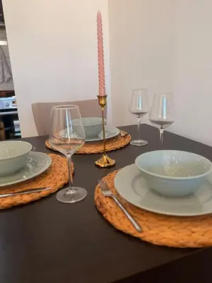 a table with plates and wine glasses and a candle at Natalie Apartment in Niš