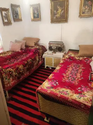 a bedroom with two beds and a table and pictures on the wall at Konak Anja