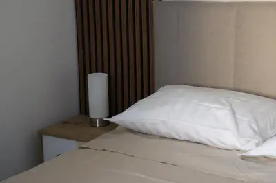 a bed with a white pillow and a lamp on a night stand at Central House Niš in Niš