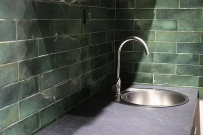a bathroom with a sink and a green tiled wall at Central House Niš in Niš