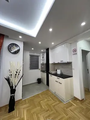 a kitchen with white cabinets and a vase of flowers at Apartman Centar LUX in Vrnjačka Banja