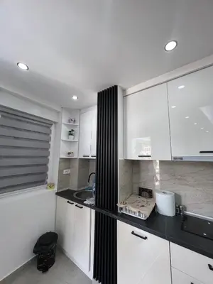 a kitchen with white cabinets and a black counter top at Apartman Centar LUX in Vrnjačka Banja