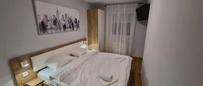 a bedroom with a bed with a picture on the wall at 15th Corner Apartment in Niš