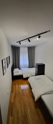a bedroom with three beds and a wooden floor at 15th Corner Apartment in Niš