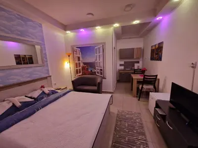 a bedroom with a large bed and a living room at Apartmani Pejovic in Niš