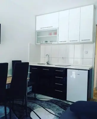 a kitchen with a sink and a counter with chairs at Apartman Smilic Lukovska banja in Lukovo