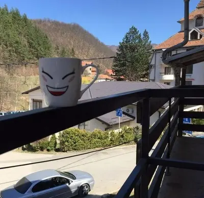 a cup with a face drawn on it sitting on a balcony at Apartman Smilic Lukovska banja in Lukovo