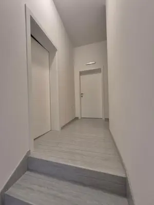 an empty hallway with a white door and a stairway at Oaza apartman in Soko Banja