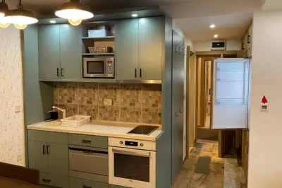 a kitchen with blue cabinets and a stove and microwave at Central Konaci Apartments & Studio by Husky in Kopaonik