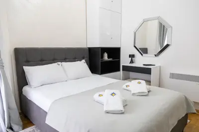 a bedroom with a white bed with towels on it at Apartman Sunce Lux N in Vrnjačka Banja