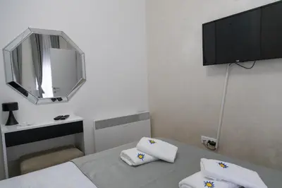 a small white room with a bed and a mirror at Apartman Sunce Lux N in Vrnjačka Banja