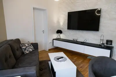 a living room with a couch and a tv on a wall at Apartman Sunce Lux N in Vrnjačka Banja
