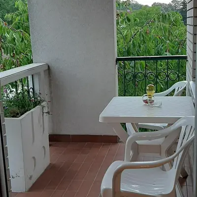 a white table and chairs on a balcony with a glass of wine at Apartman Jezero in Vrnjačka Banja