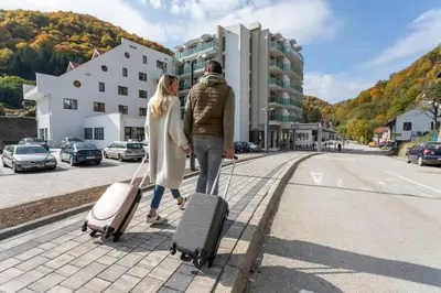 a man and woman walking down a street with their luggage at Hotel Bela Jela in Lukovo