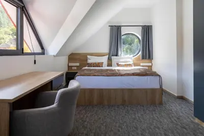 a bedroom with a bed and a desk and two chairs at Hotel Bela Jela in Lukovo