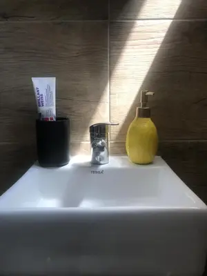 a bathroom sink with a yellow soap dispenser on it at Riseup apartman in Niš