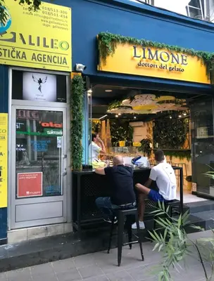 two men sitting at a table outside of a restaurant at Riseup apartman in Niš