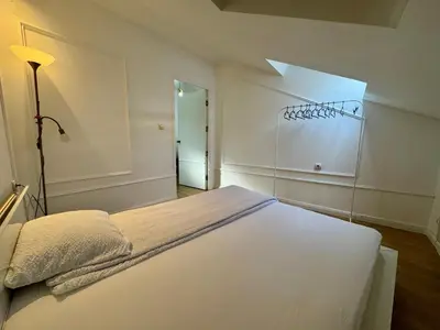 a white bedroom with a bed and a light at Riseup apartman in Niš