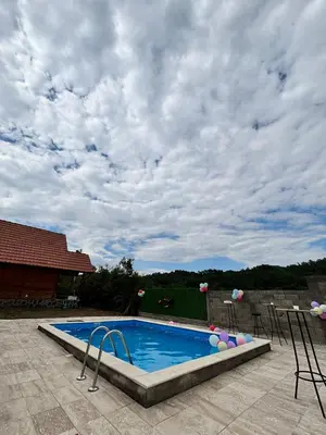 a swimming pool with chairs and a cloudy sky at Vikendice Jovicic in Bukorovac