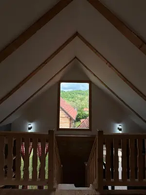 an attic room with a window and a staircase at Vikendice Jovicic in Bukorovac