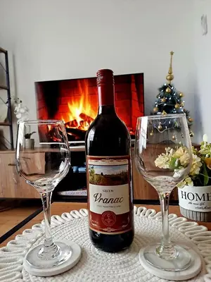 a bottle of wine and two wine glasses on a table at Apartman Srećko Lux in Vrnjačka Banja