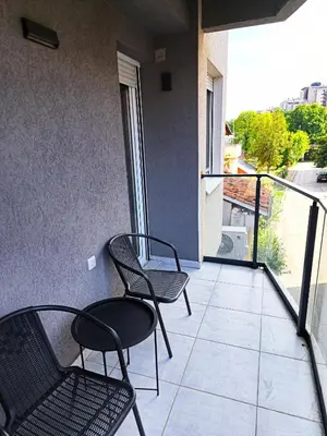 two chairs and a table on a balcony at ALDA Apartmani Vranje in Vranje