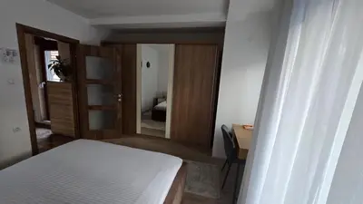 a bedroom with a bed and a desk and a mirror at ALDA Apartmani Vranje in Vranje