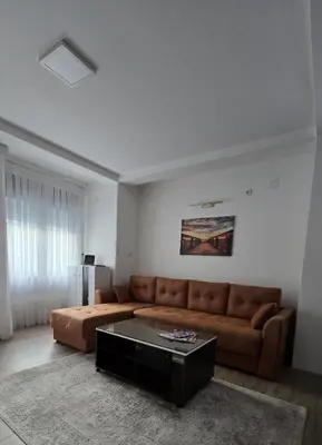 a living room with a brown couch and a coffee table at ALDA Apartmani Vranje in Vranje
