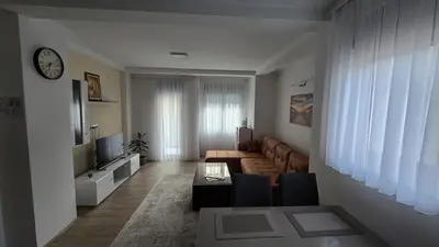 a living room with a couch and a clock on the wall at ALDA Apartmani Vranje in Vranje