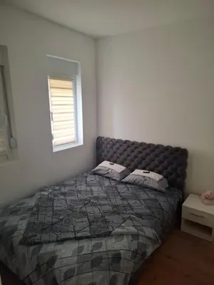 a bedroom with a bed with a comforter and a window at Apartman Jelena AS in Vrnjačka Banja