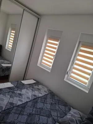 a bedroom with two windows and a mirror at Apartman Jelena AS in Vrnjačka Banja